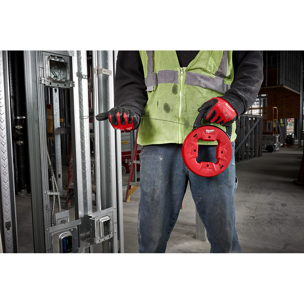 Worker in safety vest holding red Milwaukee fish tape reel with coiled steel cable.