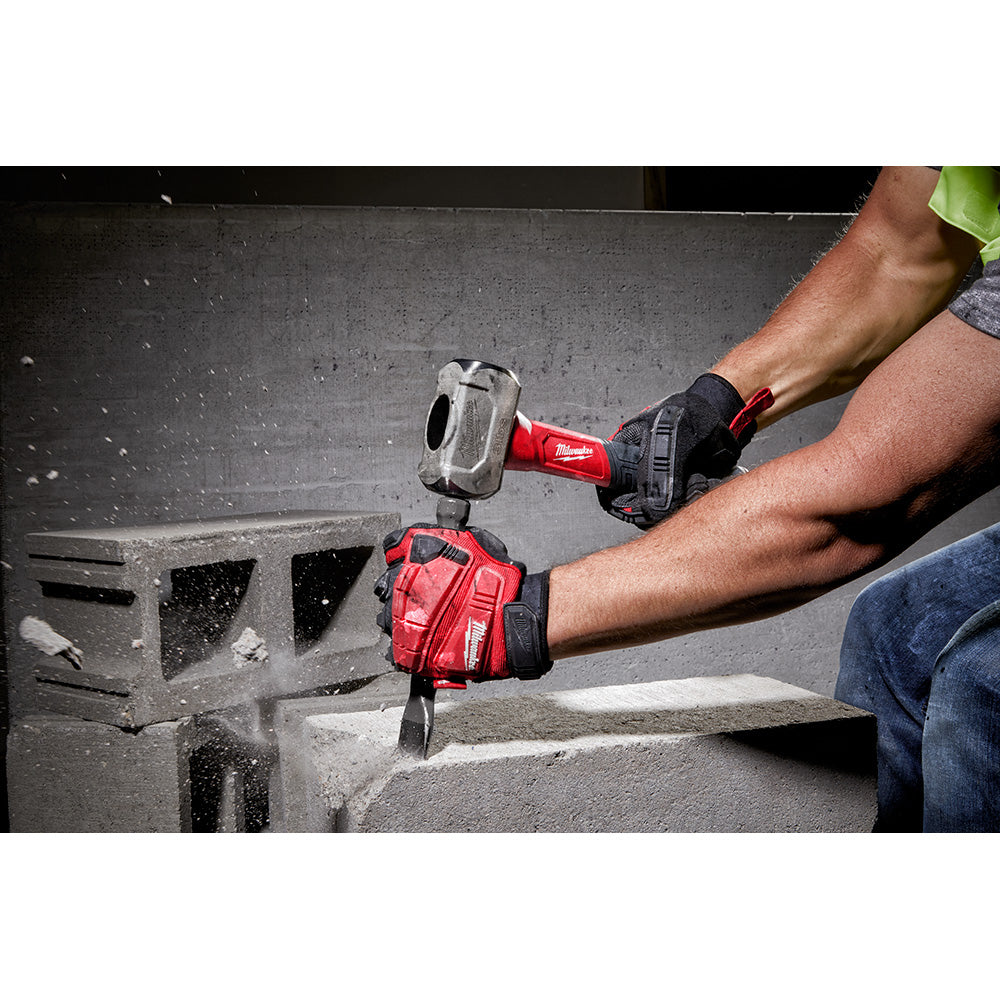 Milwaukee drilling hammer with red handle being used to strike concrete block by person wearing red and black work gloves.