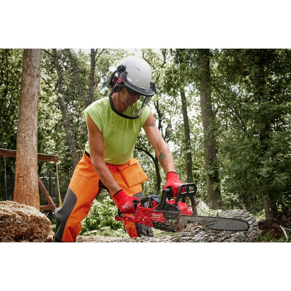 Worker wearing white hard hat with attached clear mesh face shield while operating chainsaw.