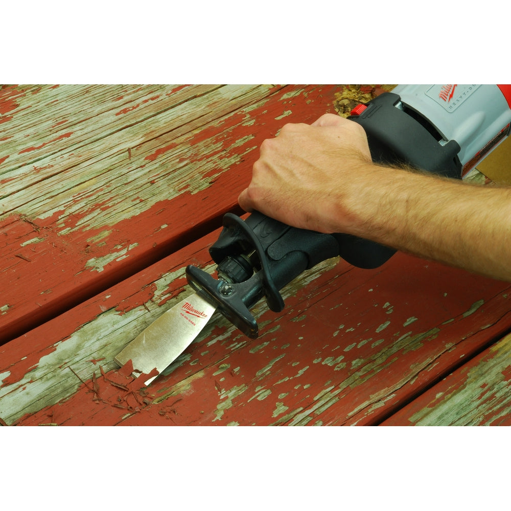 Milwaukee scraper blade with black handle being used to remove paint from wooden surface.