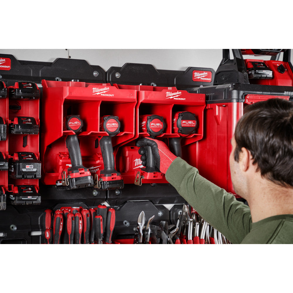 Red and black Milwaukee PACKOUT tool station with organized compartments holding power tools, hand tools, and drill bits.