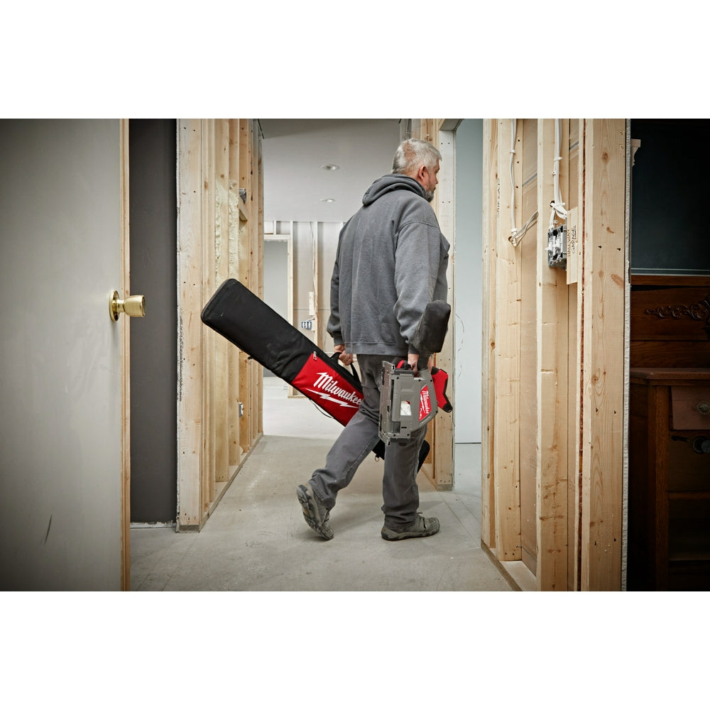 Black and red Milwaukee guide rail bag worn across worker's back on construction site.
