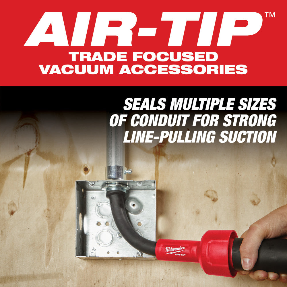 Red and black AIR-TIP conduit line puller attachment being held near an electrical outlet box on wooden surface.