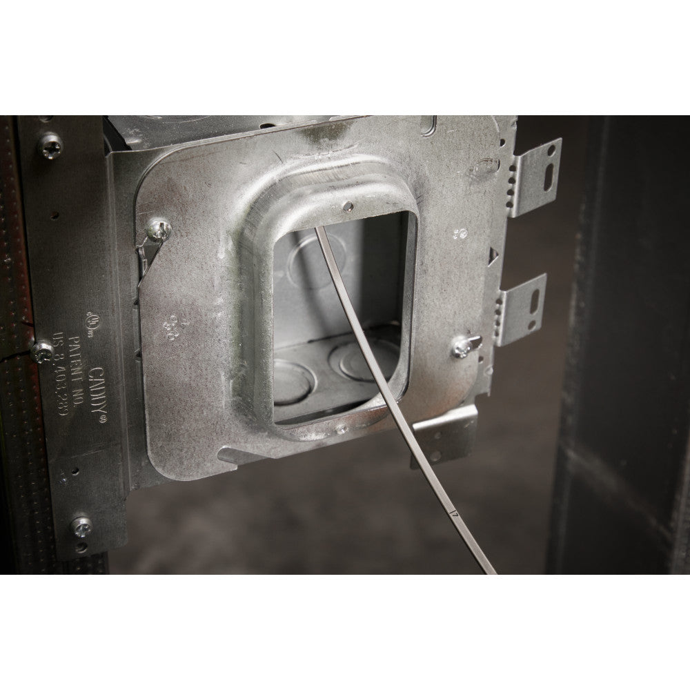 Stainless steel fish tape being threaded through an electrical junction box mounted on metal framing.