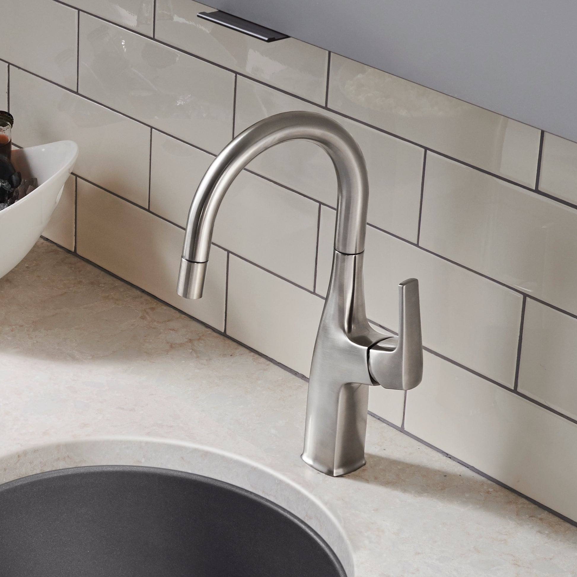 Stainless steel bar faucet with curved spout and single lever handle installed above a sink.
