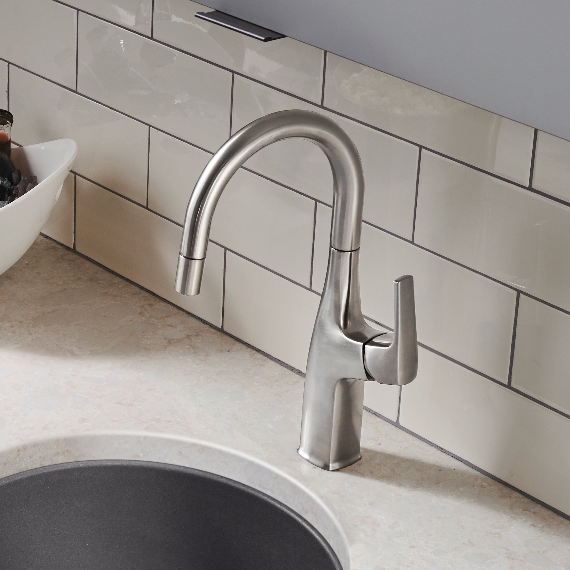 Stainless steel bar faucet with curved spout and single lever handle installed above a sink.