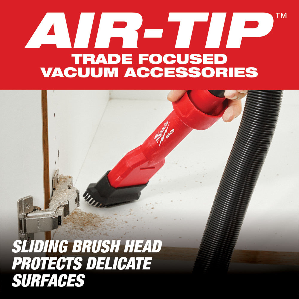 Red and black Milwaukee AIR-TIP utility brush tool with sliding brush head attachment connected to vacuum hose.