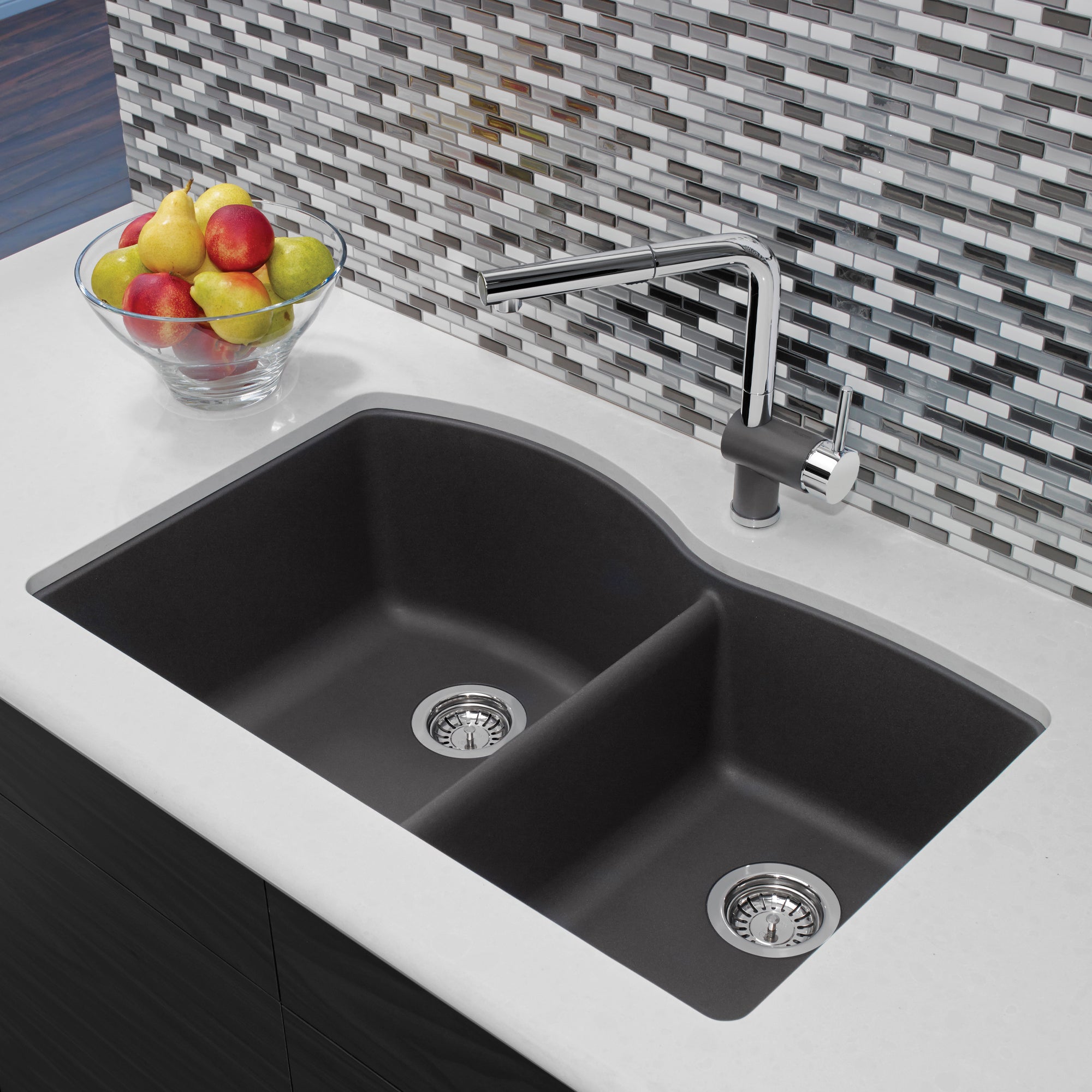 Dark gray undermount kitchen sink with two bowls and chrome faucet installed in white countertop.