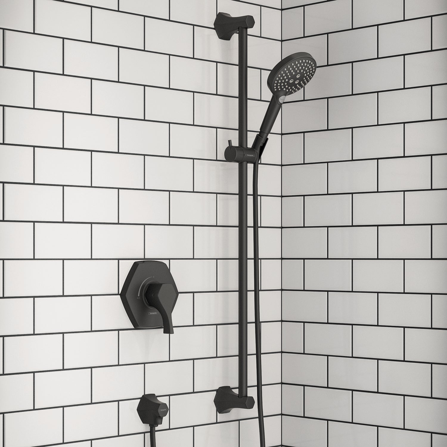 Matte black wall-mounted shower bar with handheld showerhead, valve control, and water outlet against white subway tile.