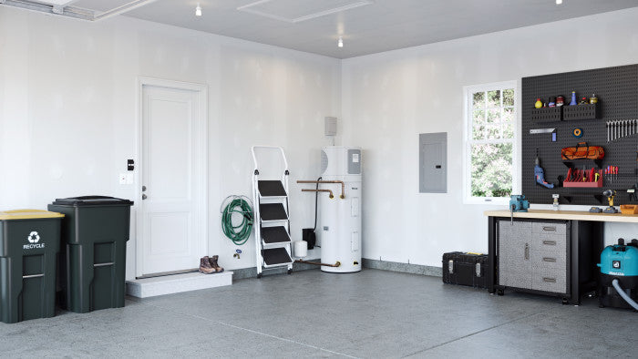 White cylindrical electric heat pump water heater installed in residential garage interior.