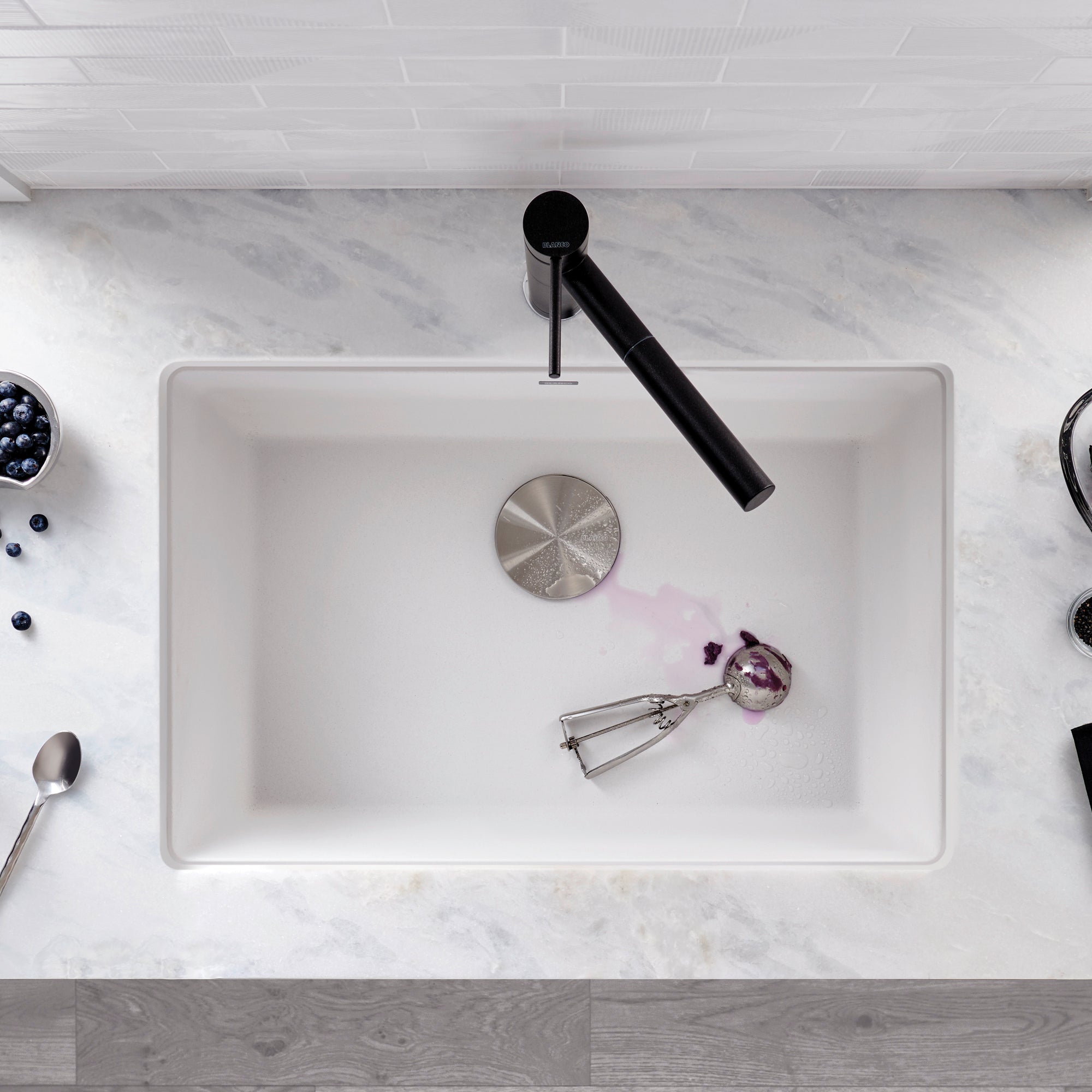 White rectangular kitchen sink with single bowl, black faucet, and drain strainer visible from above.