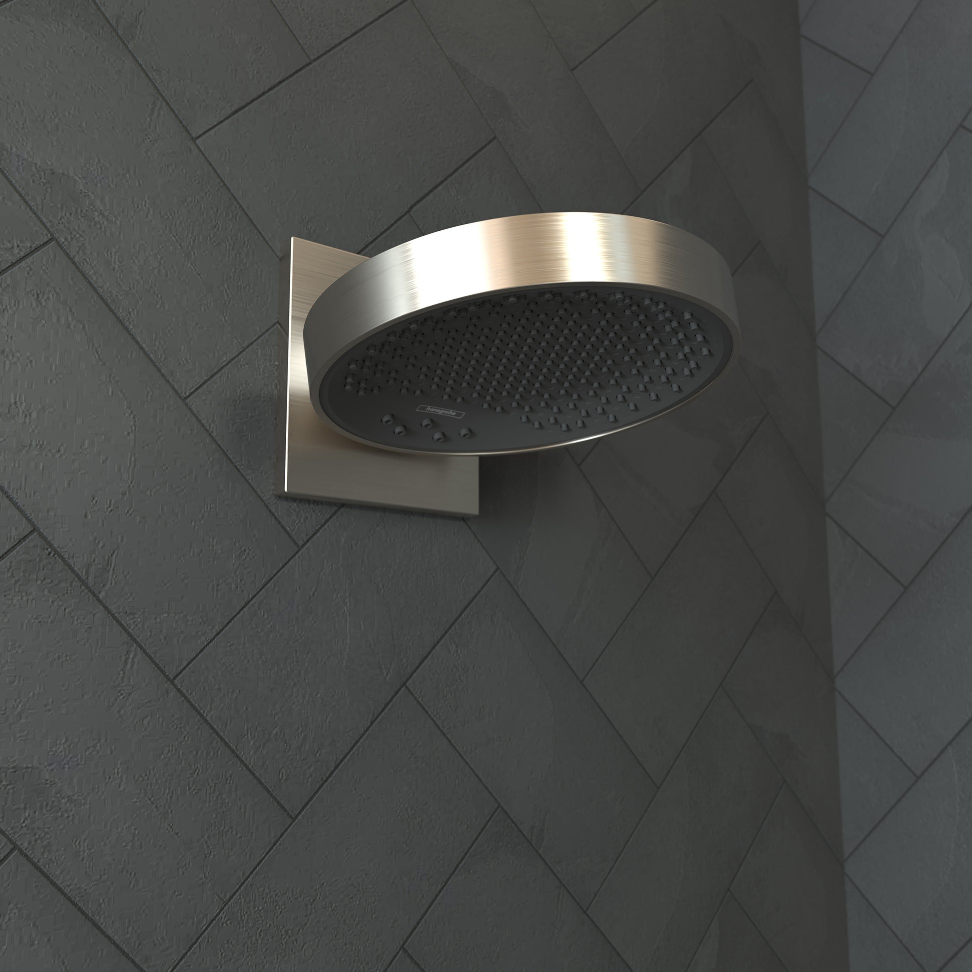 Brushed nickel round shower head with perforated face mounted on square wall connector trim against gray tile wall.