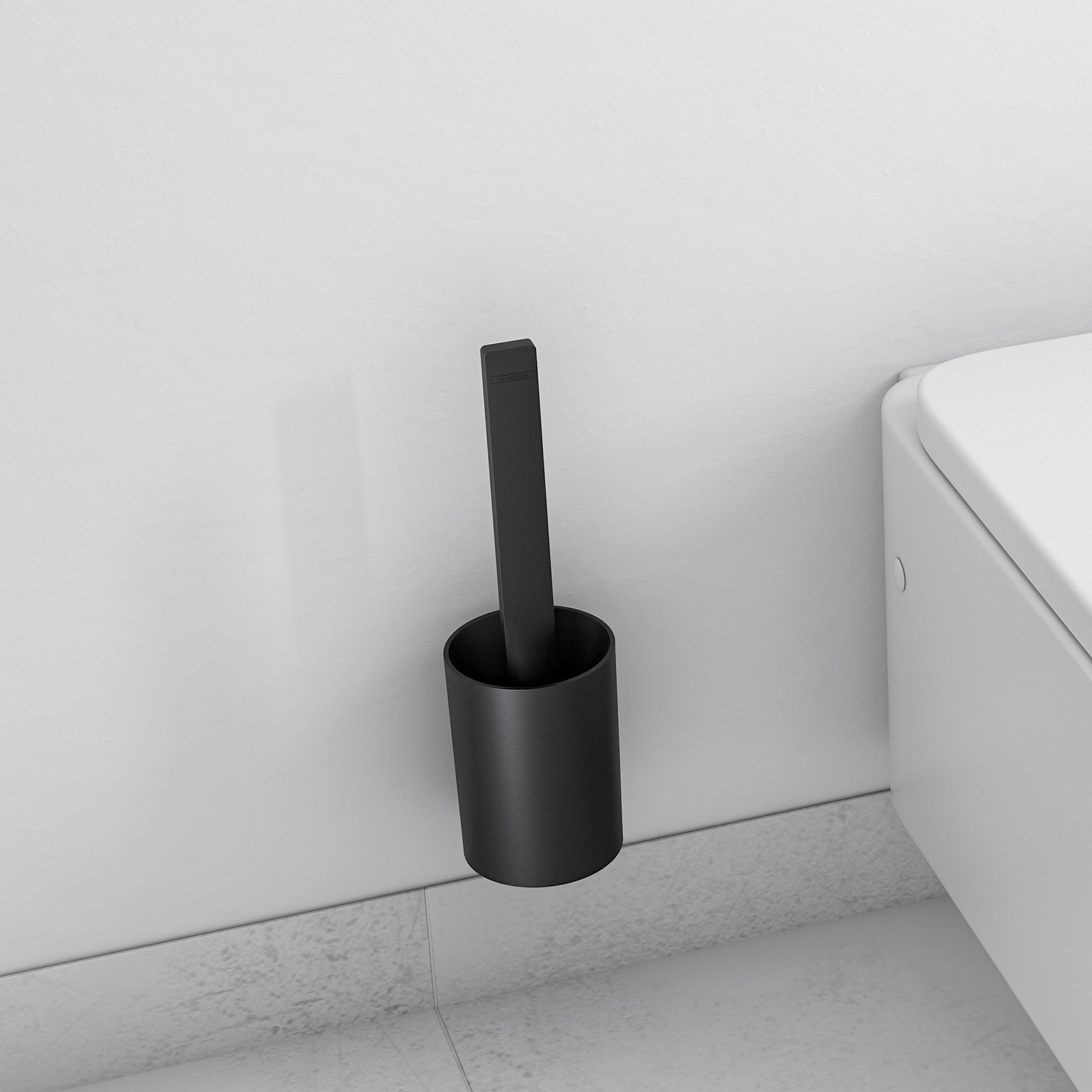 Matte black cylindrical toilet brush holder mounted on wall next to white toilet.