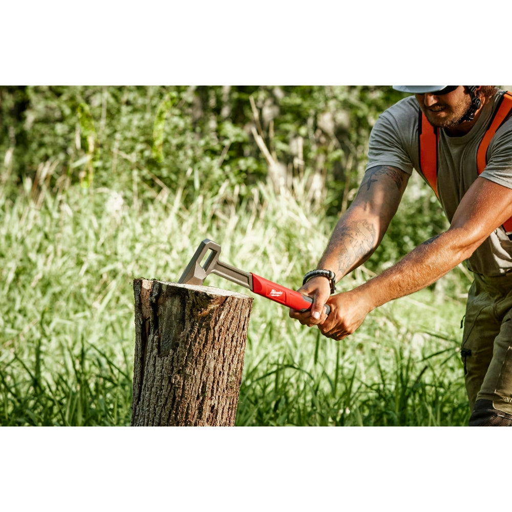 Milwaukee splitting axe with red handle positioned against a wood log outdoors.