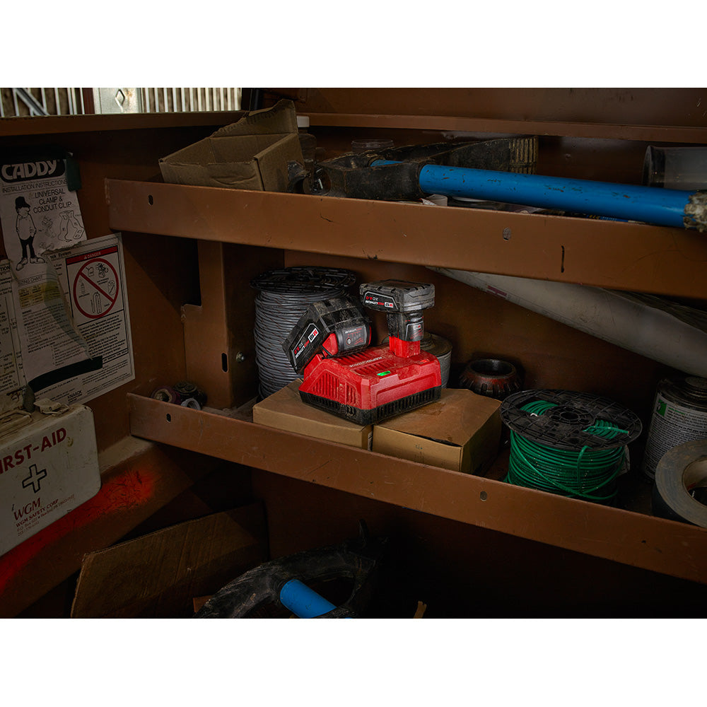 Milwaukee M18 and M12 rapid charger with red housing displayed in brown wooden storage cabinet shelf.