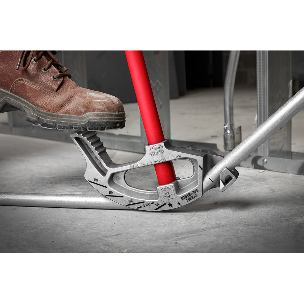 White aluminum conduit bender with red handle being used to bend silver metal tubing on concrete surface.