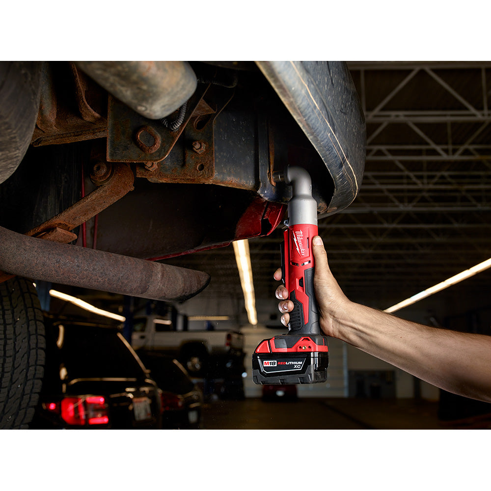 Red Milwaukee right angle impact wrench being used to tighten a bolt on a vehicle undercarriage in a garage.