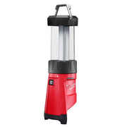 Red and black Milwaukee cordless LED lantern with handle, translucent cylindrical light chamber, and power button on lower bo