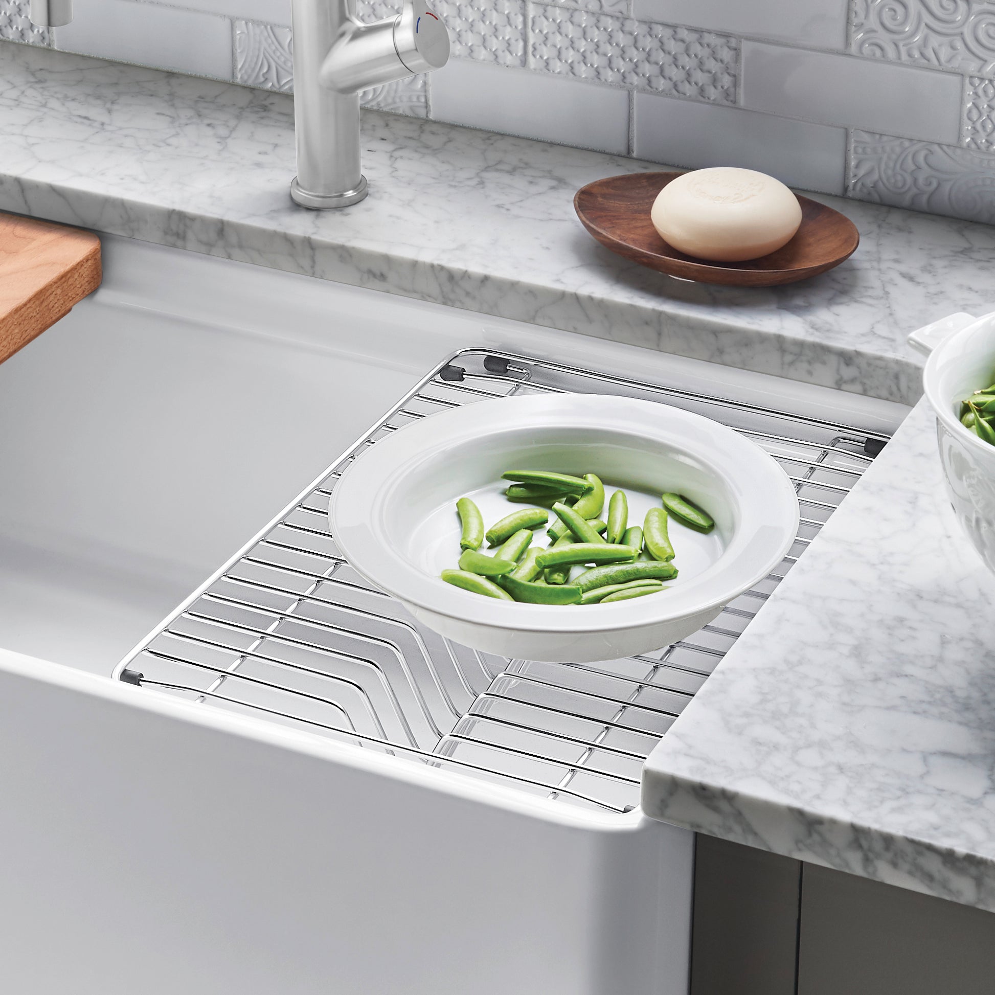 Stainless steel dish rack with linear grid pattern sitting in apron front sink basin.