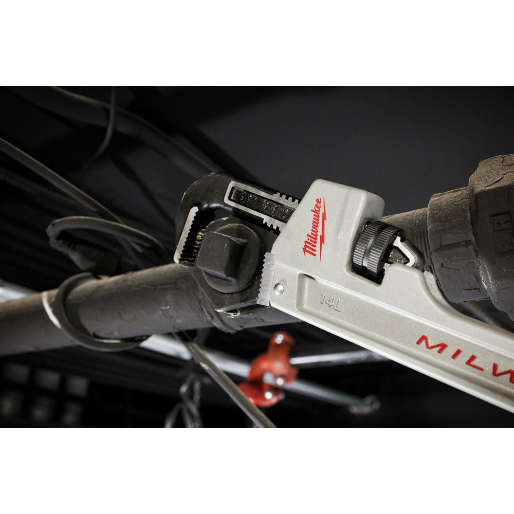 Milwaukee 14-inch aluminum pipe wrench with white handle gripping a metal pipe.