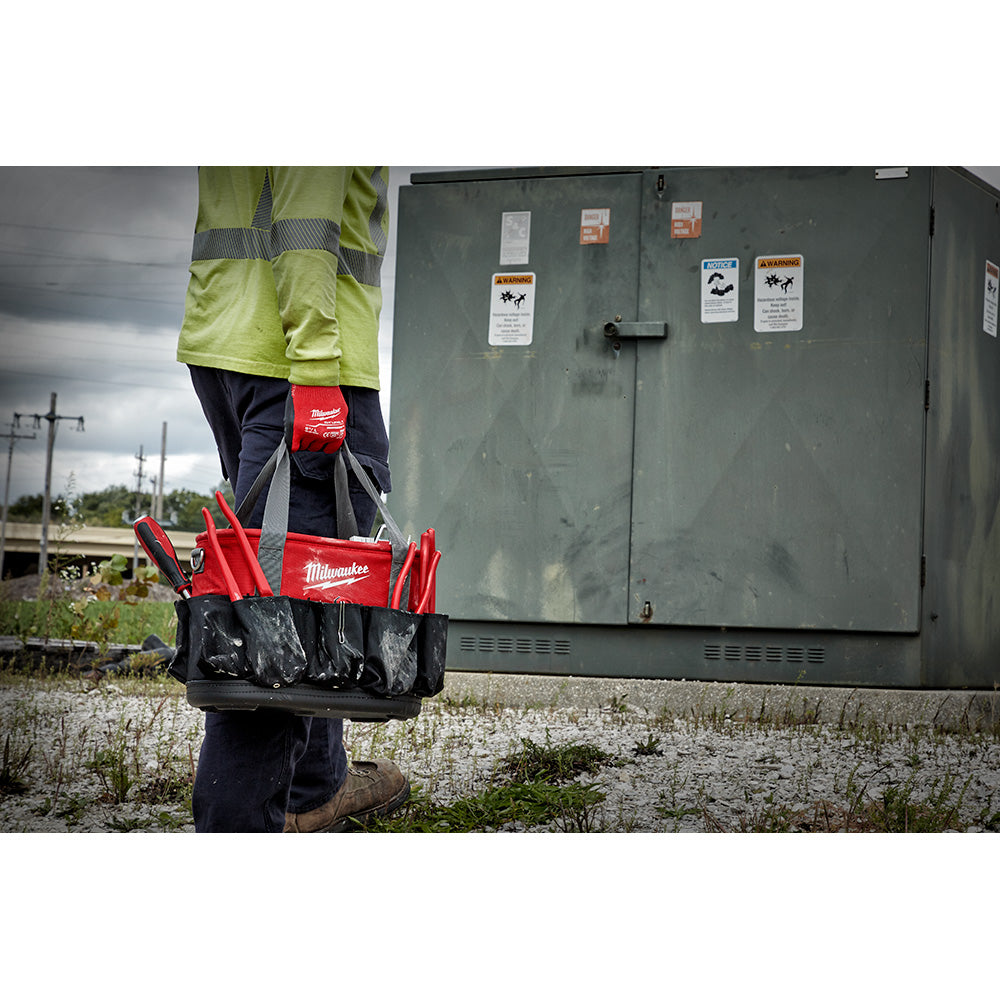 Milwaukee Underground Oval tool bag with red and black exterior, carried by worker on job site.