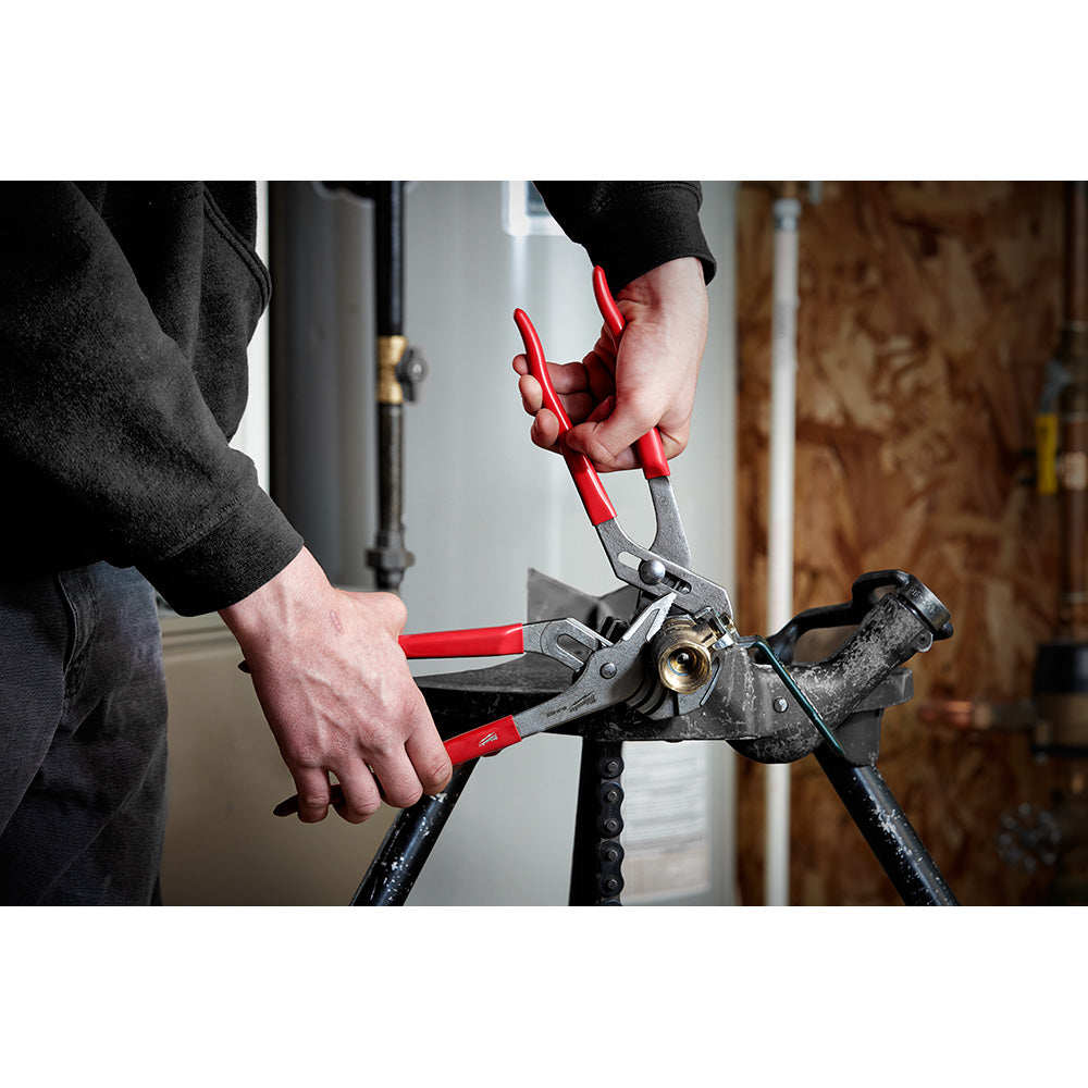 Milwaukee 10-inch pump plier with red handles and black grip, held in hand above a pipe.