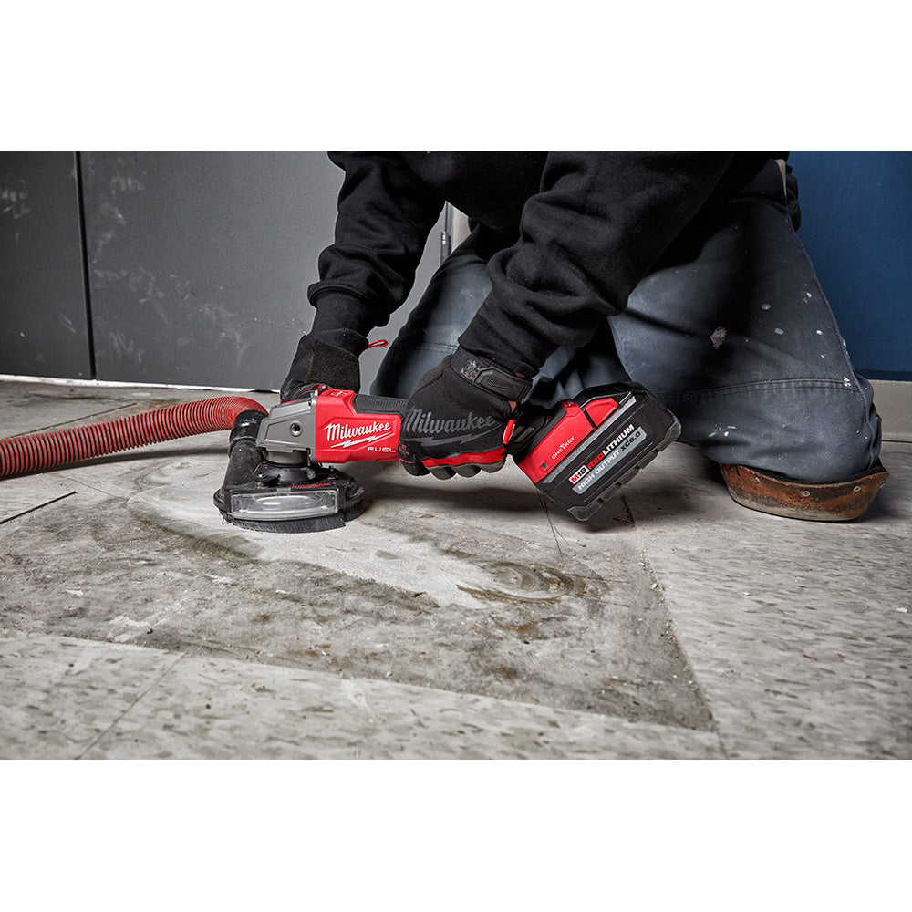 Milwaukee M18 FUEL braking grinder with red and black housing, dust collection hose, and battery pack on concrete surface.