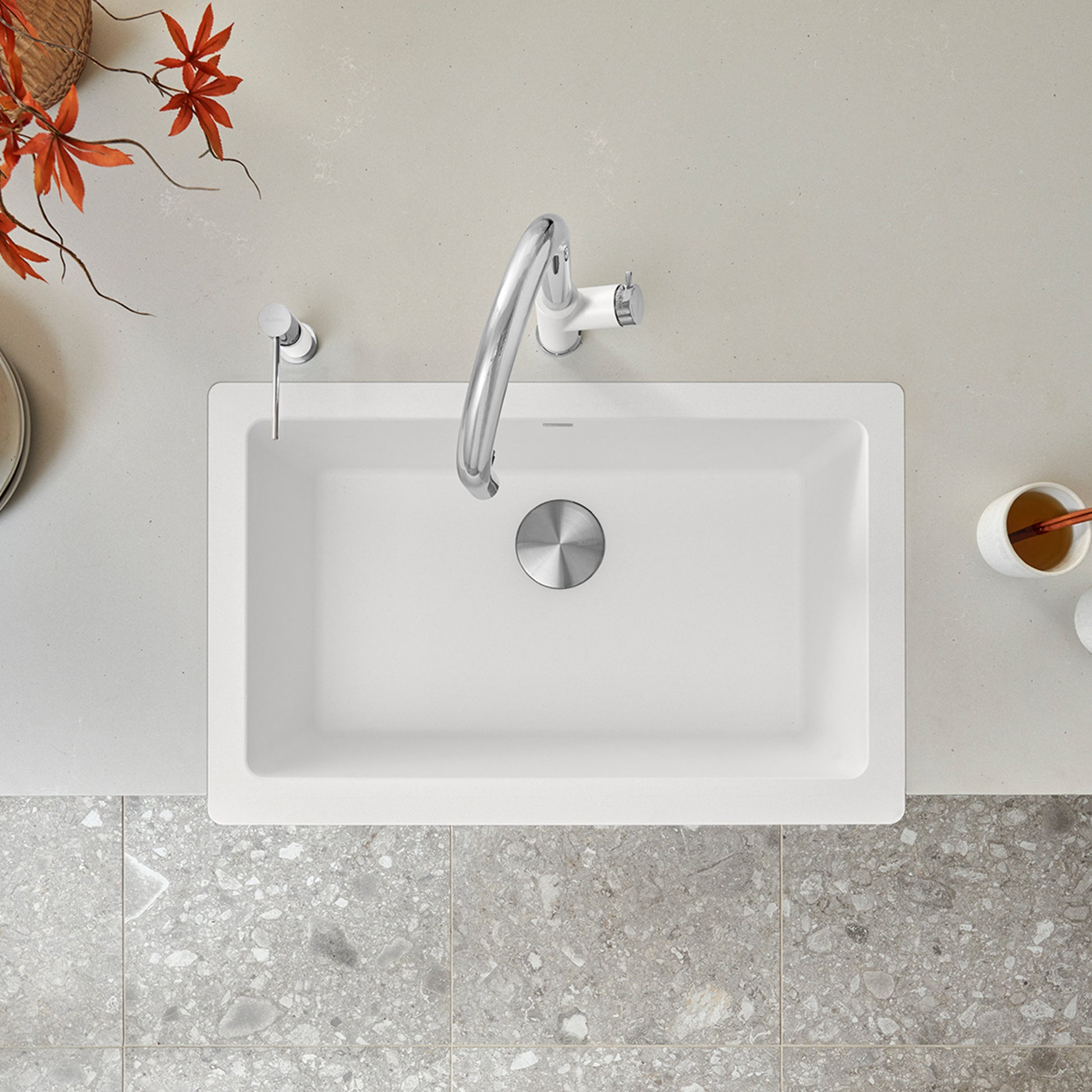 White rectangular apron farmhouse sink with single basin, chrome faucet, and stainless steel drain cover, viewed from above.