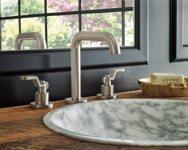 Luxe nickel widespread bathroom faucet with curved spout and two handle controls installed on marble sink.