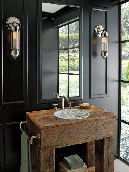 Luxe nickel widespread lavatory faucet with two handles and pop-up drain installed on wooden vanity with round marble sink.