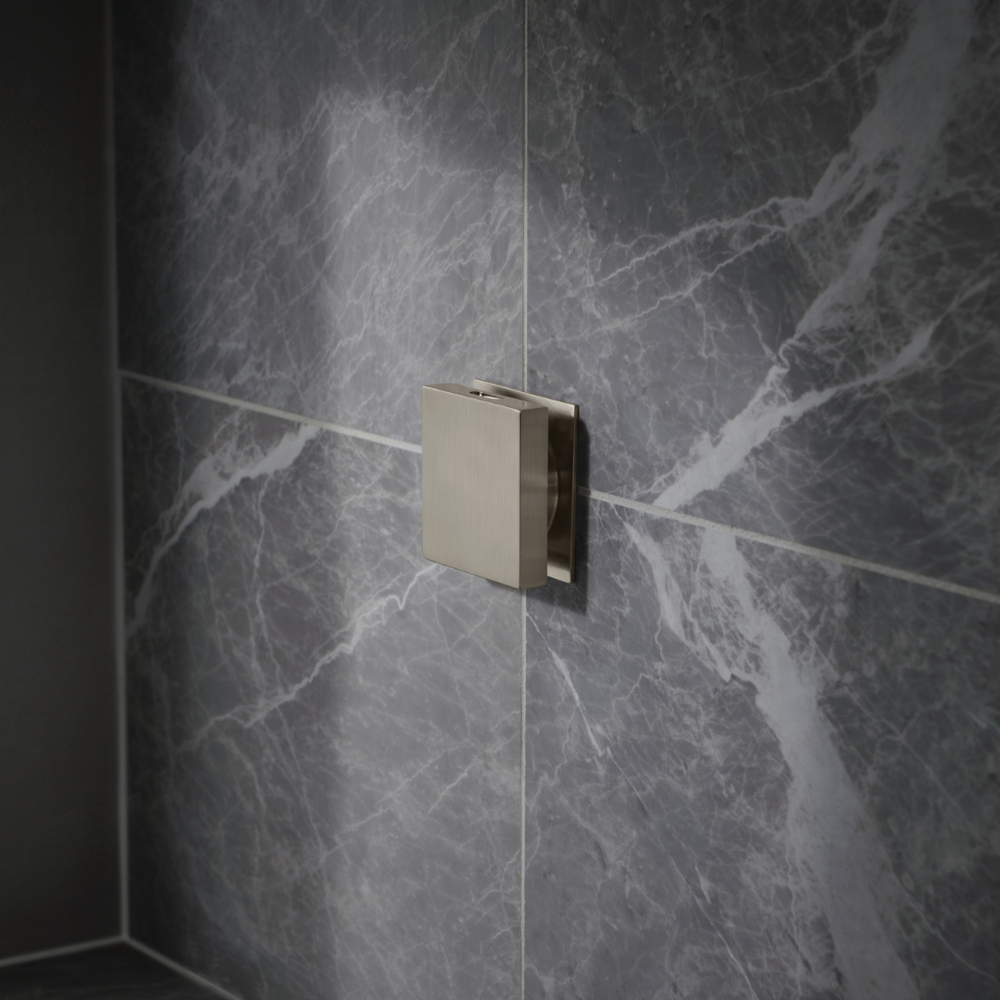 Square nickel steam shower control mounted on dark marble tile wall.