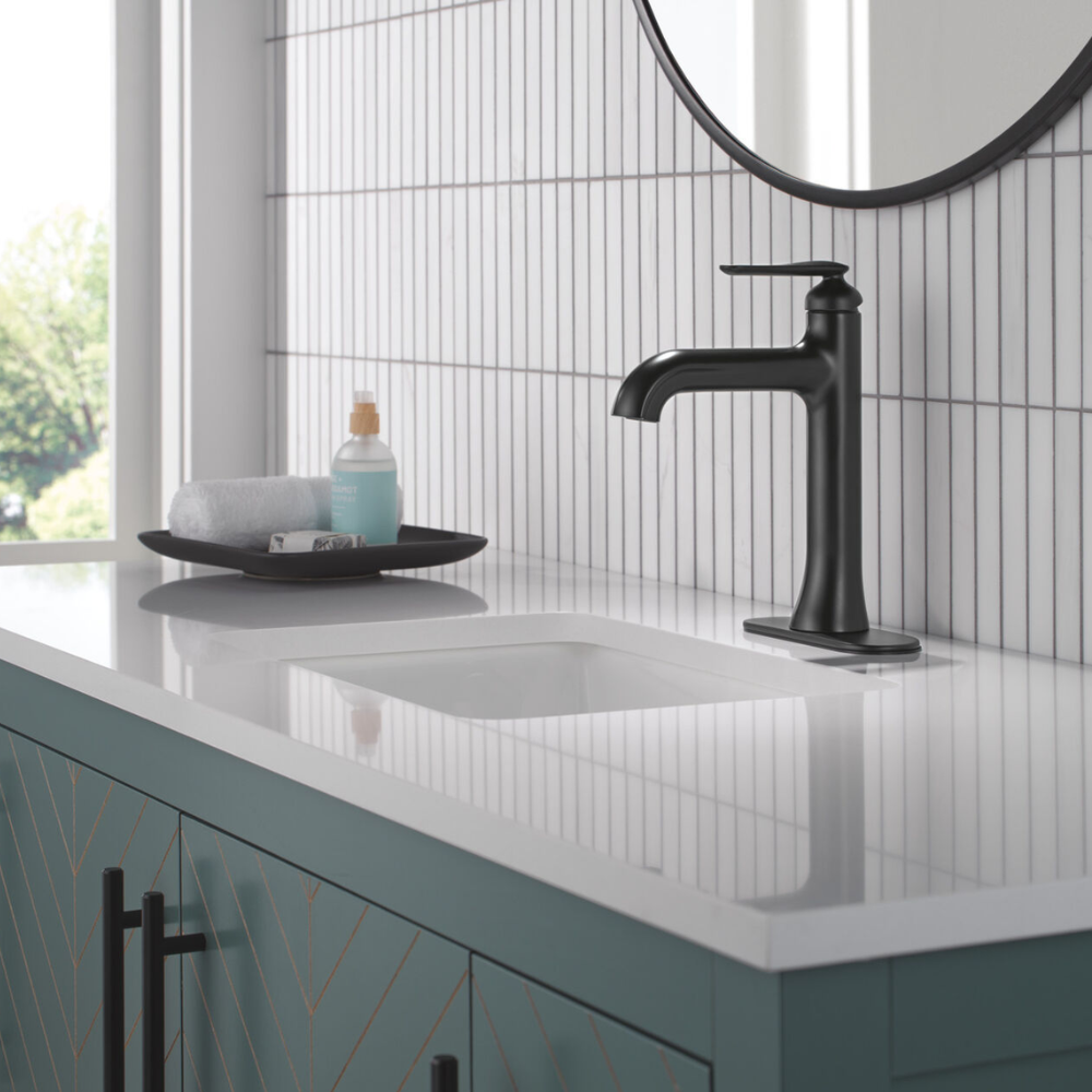 Matte black single-handle bathroom faucet with curved spout installed on white countertop sink.