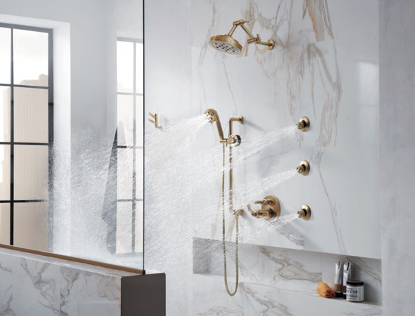 Luxe gold thermostatic valve with six shower outlets on marble wall, featuring rainfall and body spray nozzles.