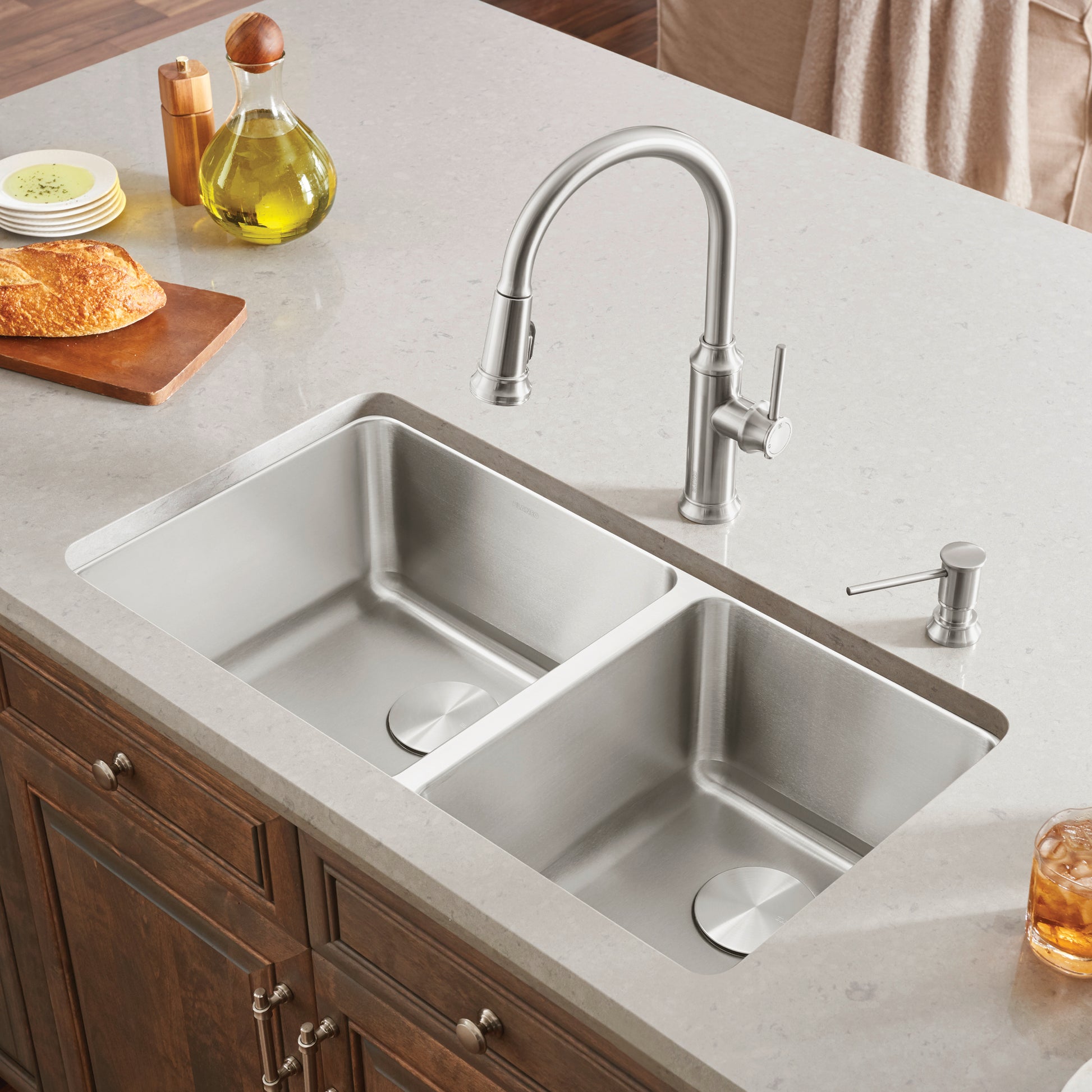 Stainless steel undermount double bowl kitchen sink with pull-down faucet and soap dispenser installed in light countertop.