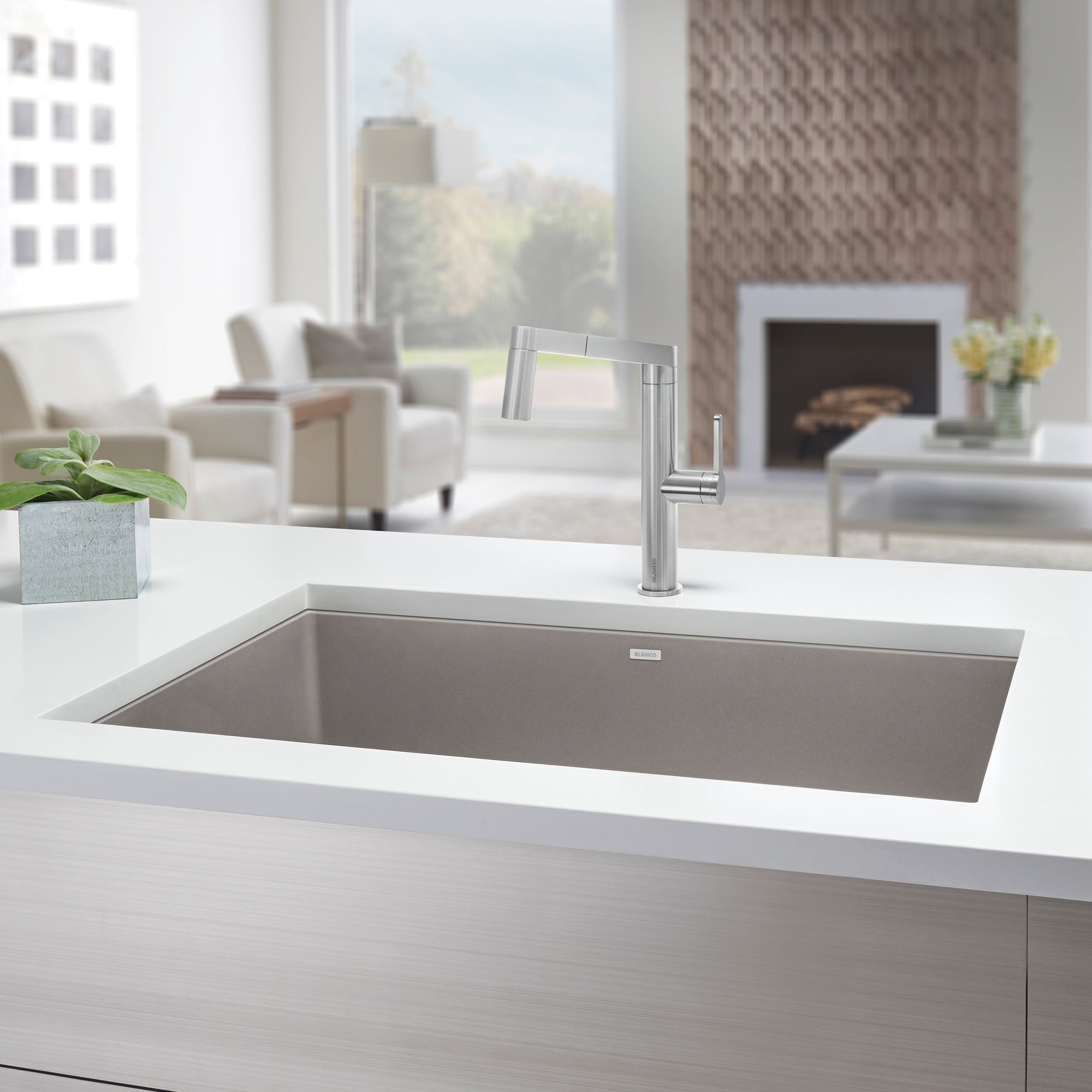 Truffle-colored undermount single bowl kitchen sink with chrome faucet installed in white countertop.