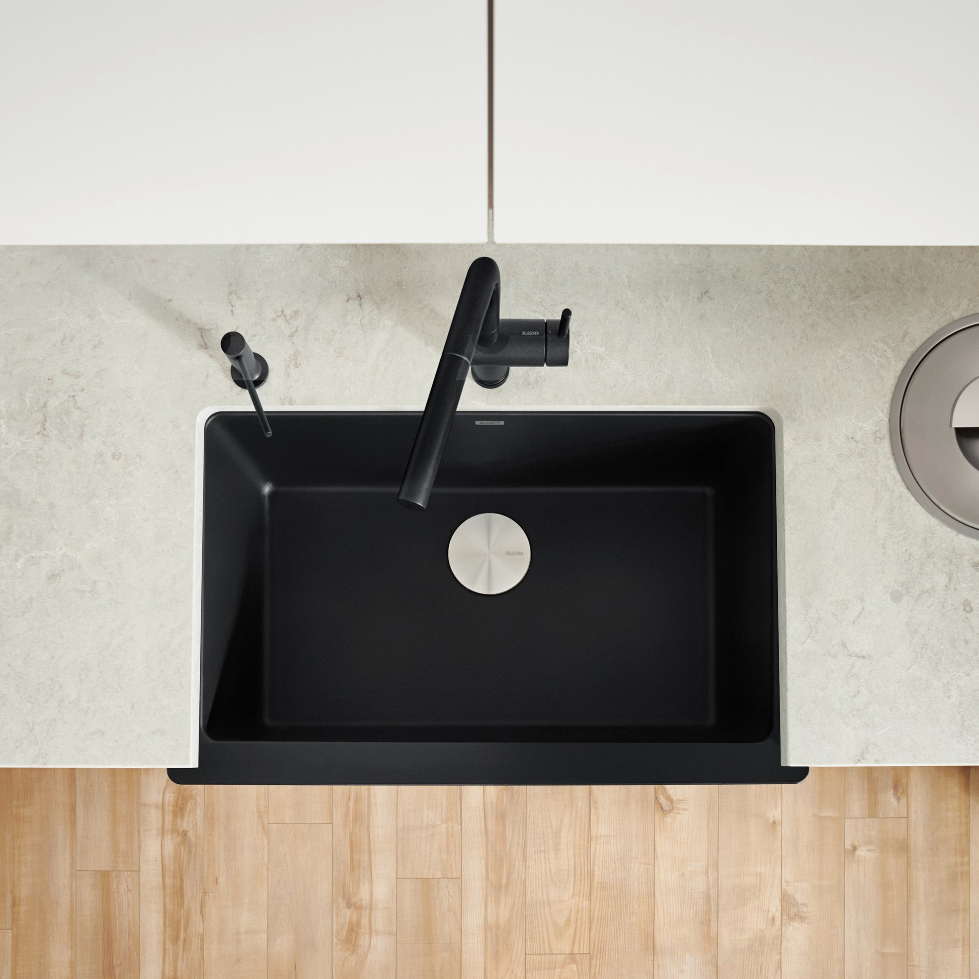 Coal black single bowl farmhouse sink with apron front and black faucet, viewed from above.