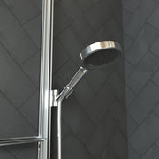 Chrome handheld showerhead with perforated face mounted on vertical rail against herringbone tile wall.