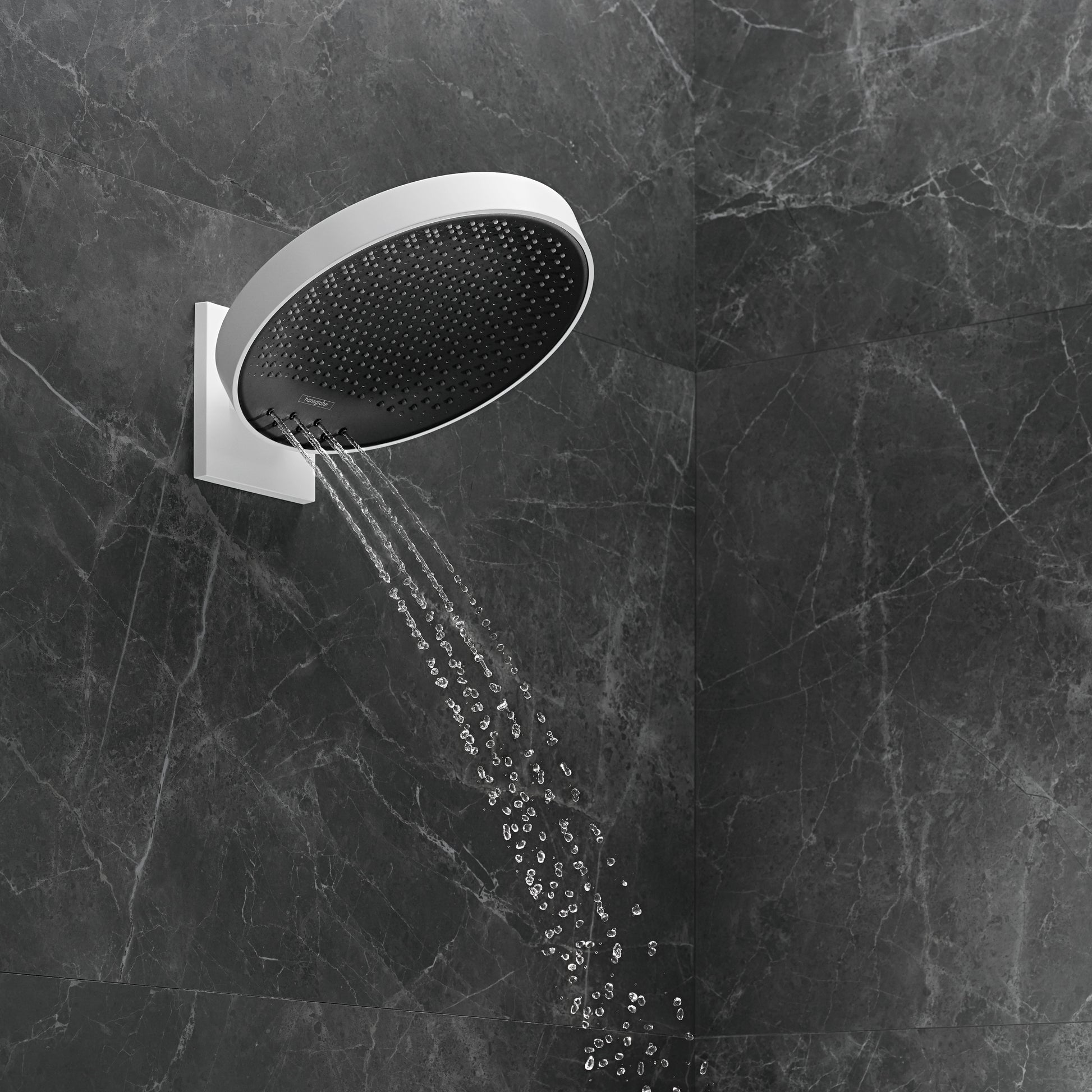 Matte white round shower head with black interior mounted on tiled wall with water spraying from multiple jets.