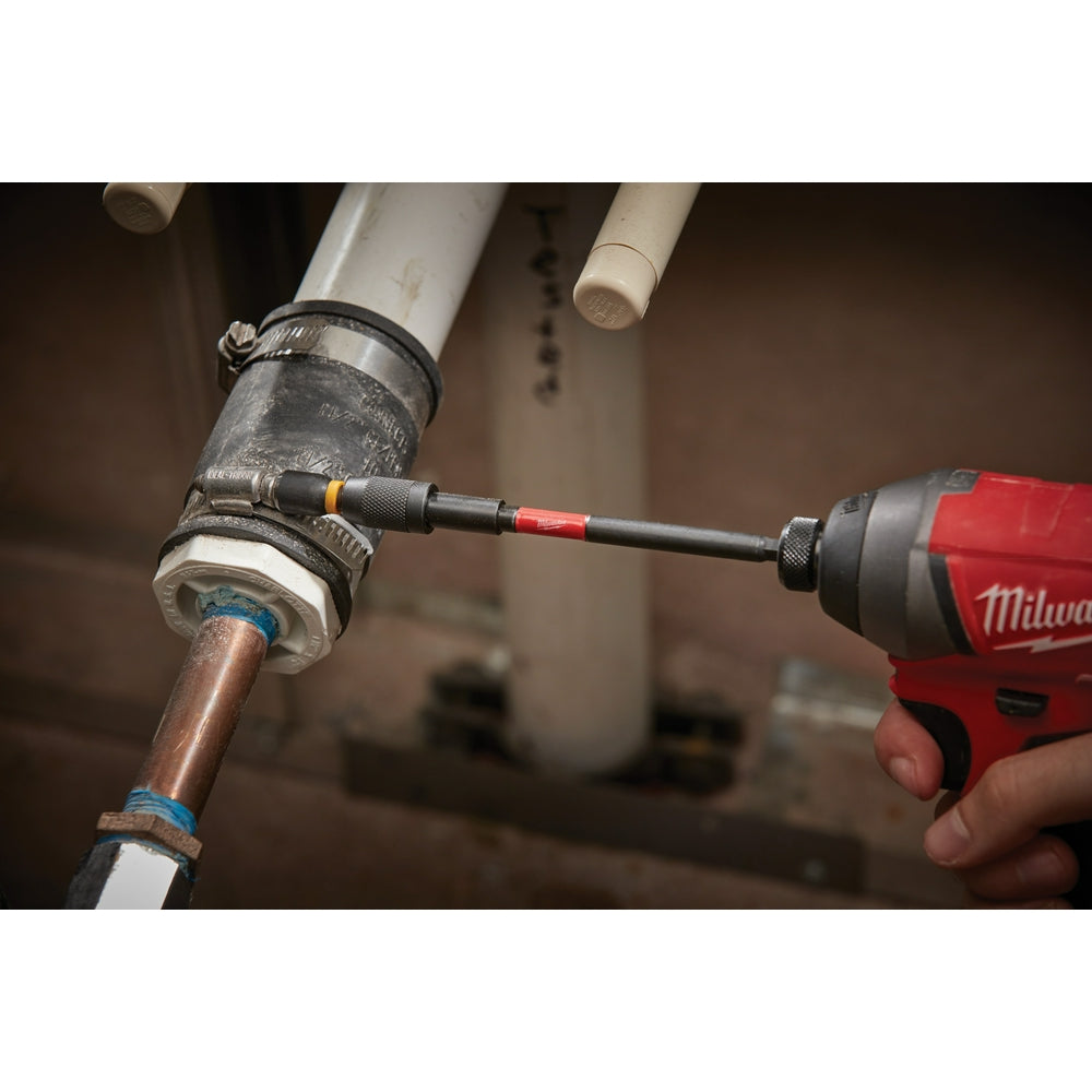Milwaukee impact locking bit holder with black and orange shaft inserted into red power drill, positioned at copper pipe fitt