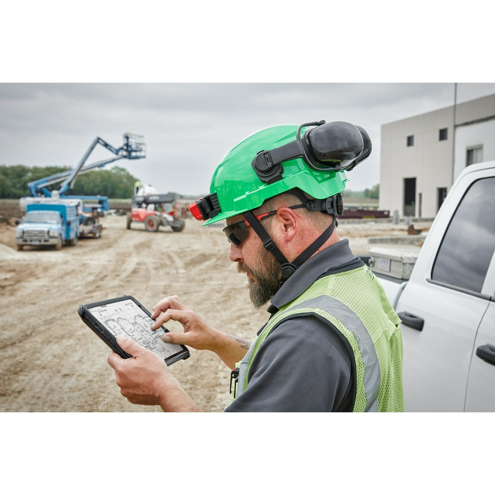 Gray safety helmet with black BOLT headlamp attachment mounted on top, worn on construction site.