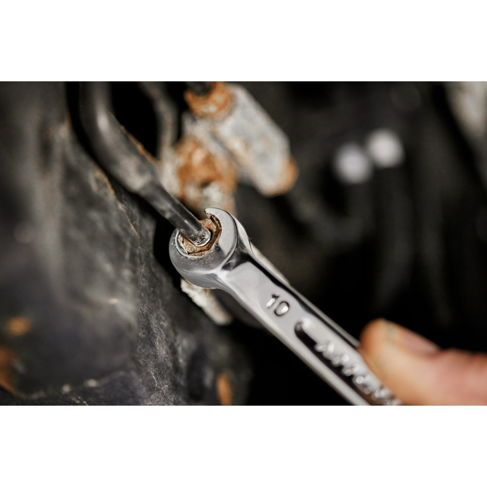 Chrome double end flare nut wrench with open ends, tightening a corroded fitting on dark metal surface.