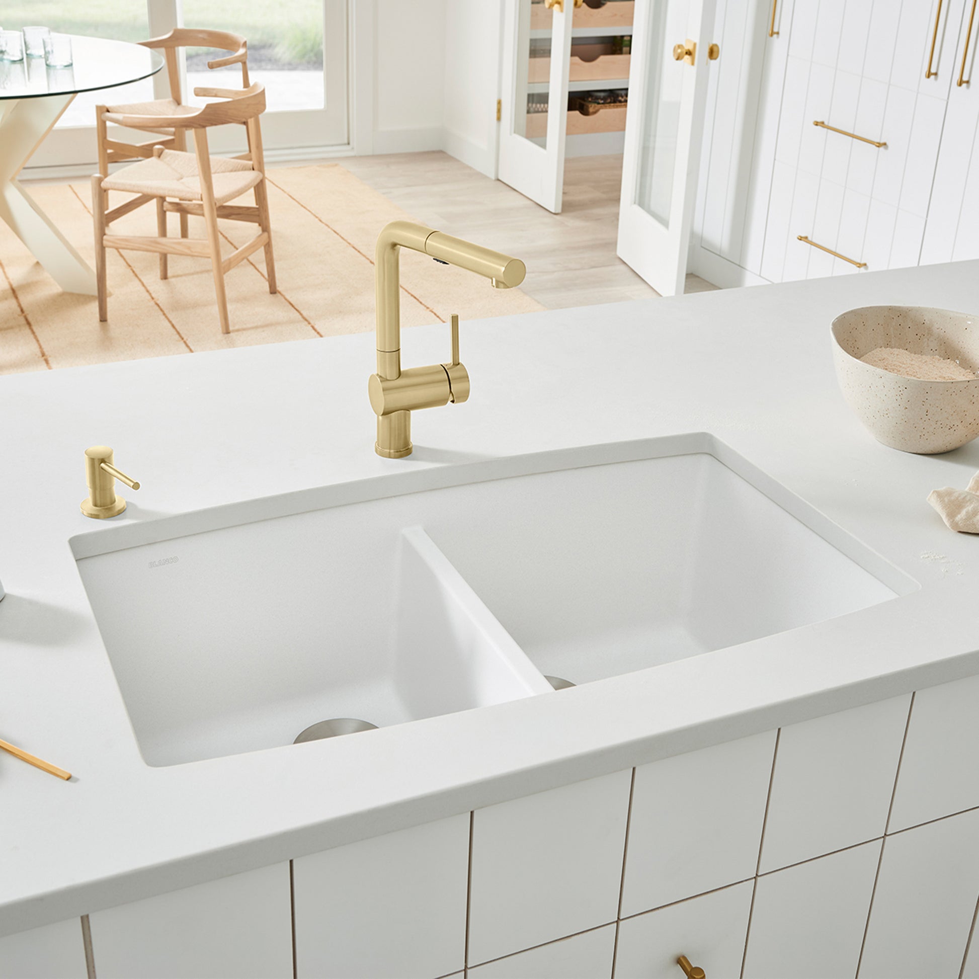 White undermount double bowl kitchen sink with two equal rectangular basins and brass faucet installed in countertop.