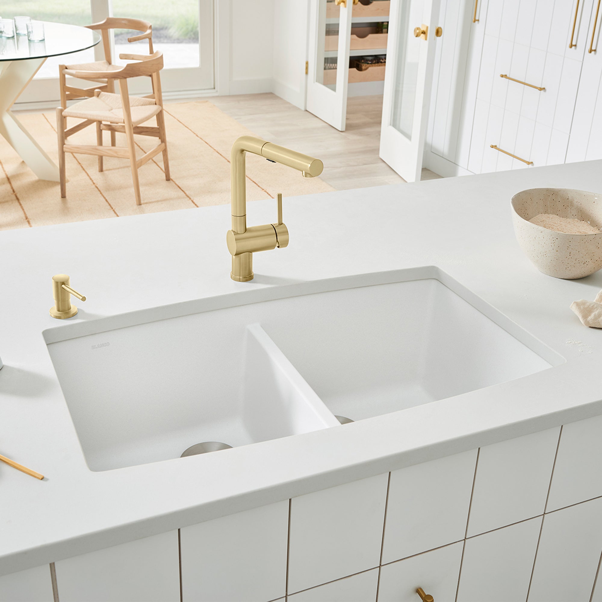 White undermount double bowl kitchen sink with two equal rectangular basins and brass faucet installed in countertop.