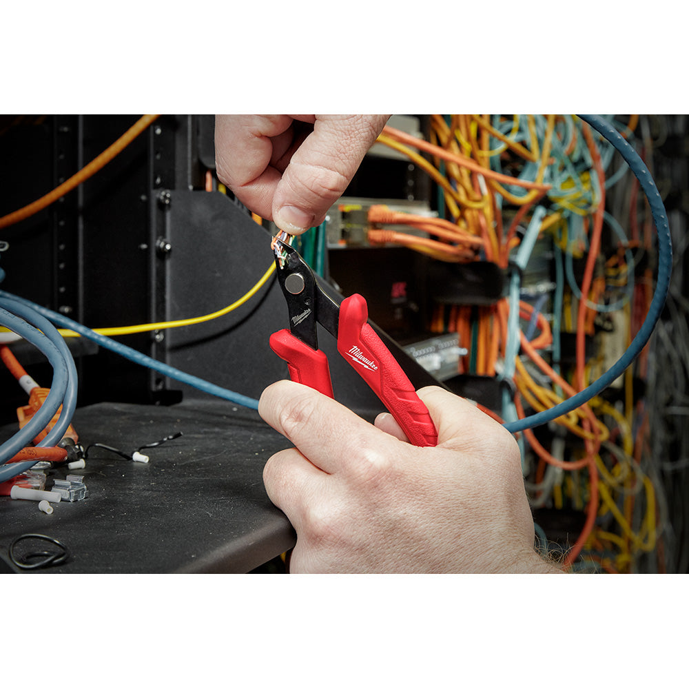 Milwaukee mini flush cutters with red handles being used to cut wire in an electrical panel.