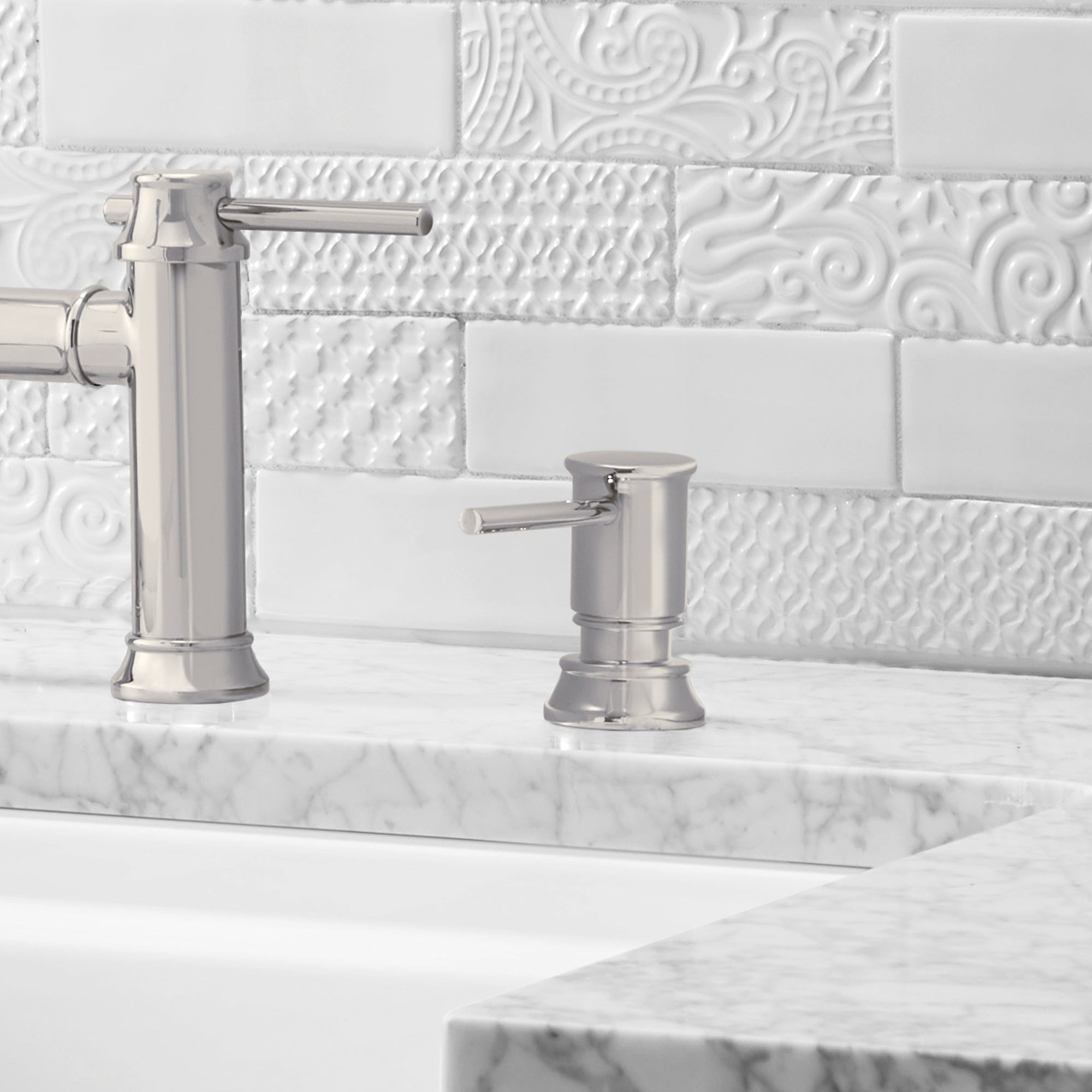Chrome soap dispenser with cylindrical pump and lever handle on marble countertop beside faucet.