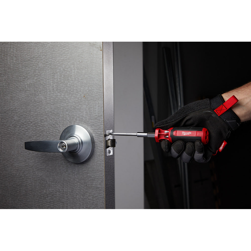 Red and black multi-bit driver with extended shaft being used on a door lock mechanism.