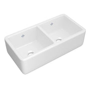 White fireclay apron front kitchen sink with two equal bowls and drainage holes.
