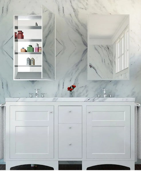 White mirrored medicine cabinet with shelves mounted above marble bathroom vanity with dual sinks.