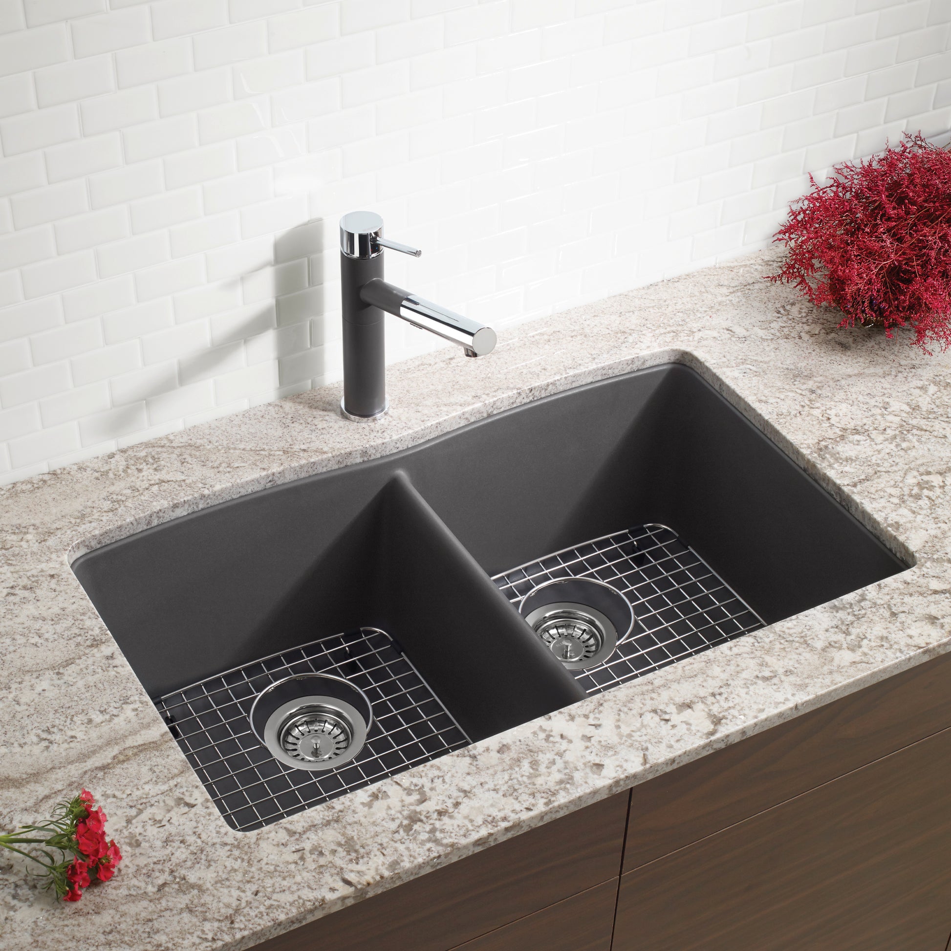 Dark gray double basin undermount sink with grid inserts and chrome faucet on light countertop.