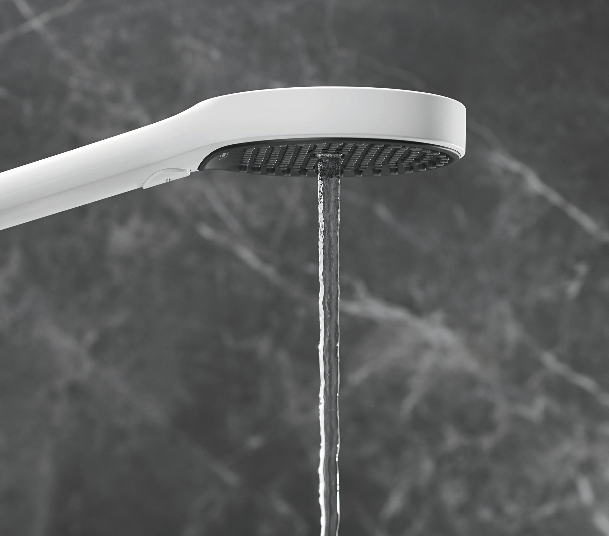 Matte white handheld showerhead with circular perforated face and curved arm, water stream visible below.